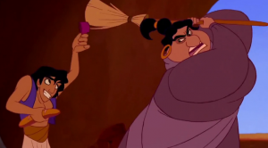 Aladdin hides from the heavy-set woman in charge of the harem who is swinging a broom at him.