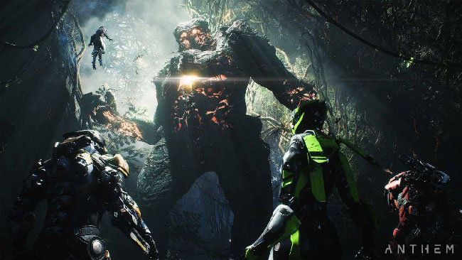 Screenshot of “Anthem,” depicting what looks like a party of four armored warriors, with a giant monster towering over them in a dark jungle.